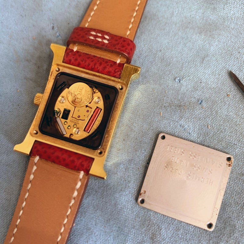 エルメスの腕時計の腕時計電池交換修理のために腕時計本体から古い電池を取り除いて、新しい電池を慎重に交換している様子
