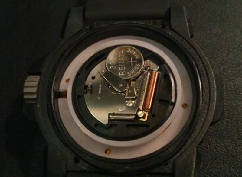 腕時計電池交換修理のために古い電池をLUMINOXルミノックス腕時計から取り除いて、新しい電池を慎重に交換している様子