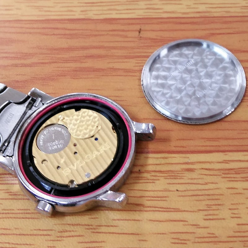 Bvlgari ブルガリ 腕時計の腕時計本体から古い電池を取り除いて、新しい電池を慎重に交換している様子