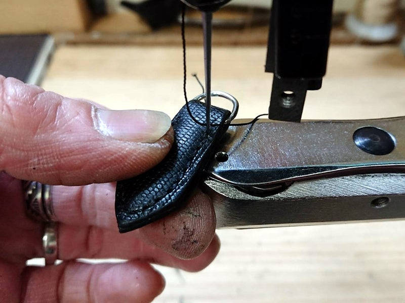 カバン・バックス修理のためにオリジナルに近い革を用いて裁断し、新しく作成した引き手スラスを八方ミシンで縫い付けている様子